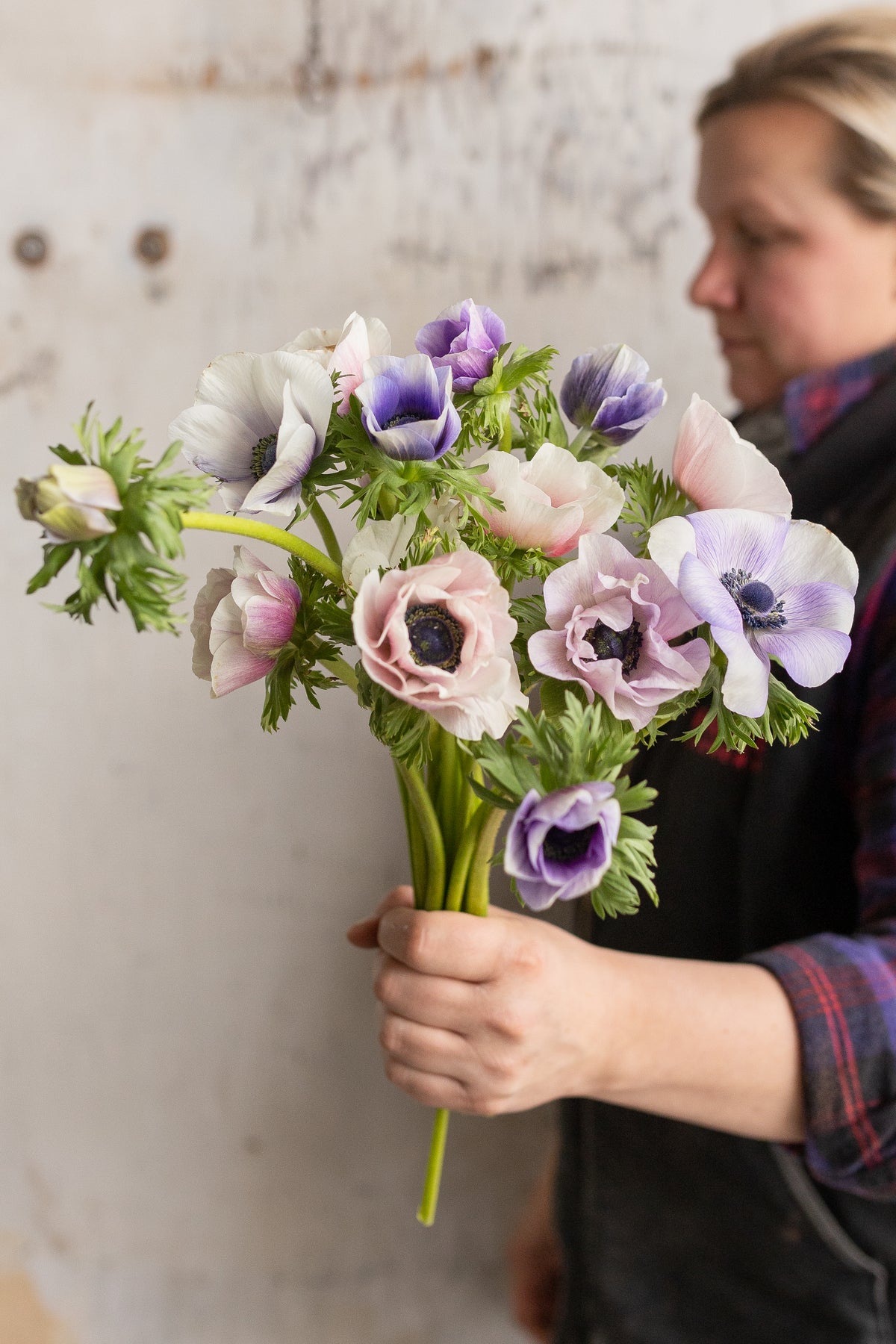 Becky holding a full bunch of pastel pink, white and lilac anemones