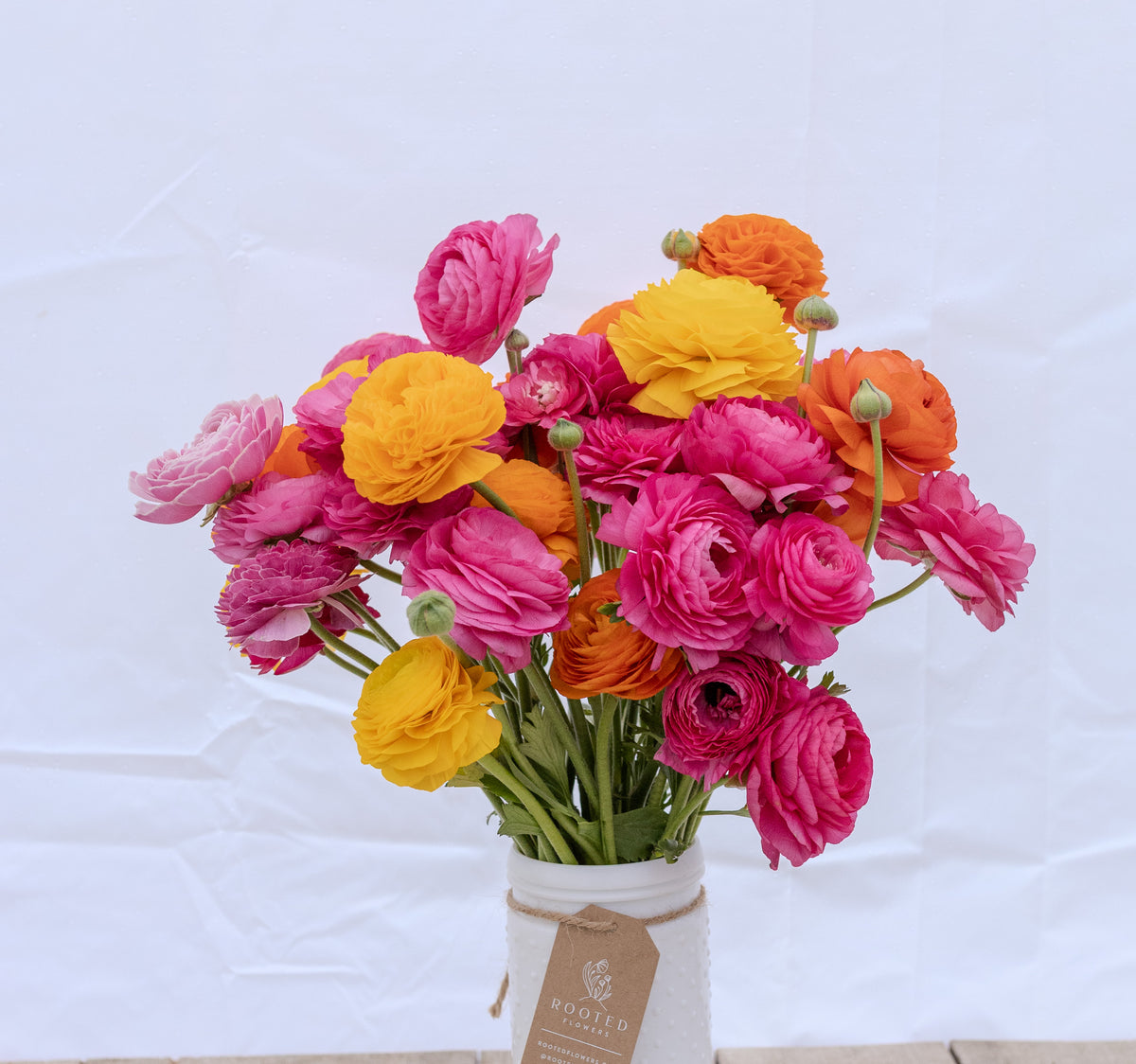 Full bunch of bright magenta, yellow and orange ranunculus blooms at Rooted Flowers